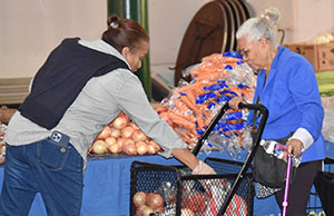 A woman helping put food in a older woman's basket