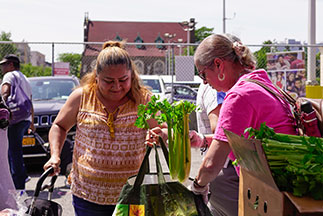 A volunteer helping a woman with bags of food. Links to Gifts of Real Estate